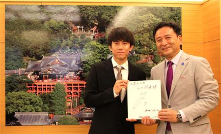 祐徳稲荷神社の写真の前で知事と平河選手がサインを持ってツーショット